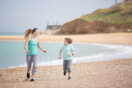 Mother with son running on the beach at morningの写真素材