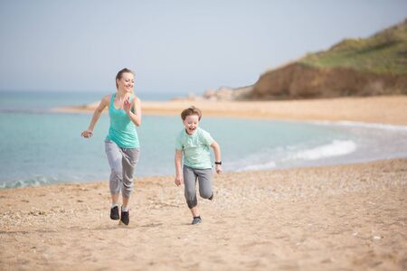 Mother with son running on the beach at morningの写真素材