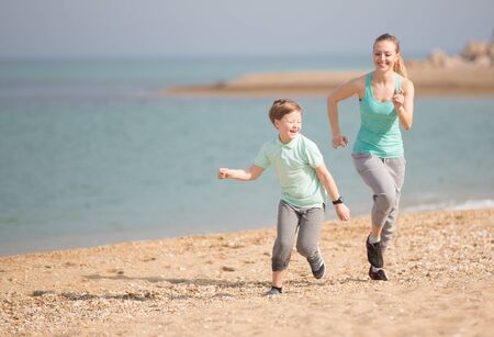 Mother with son running on the beach at morningの写真素材