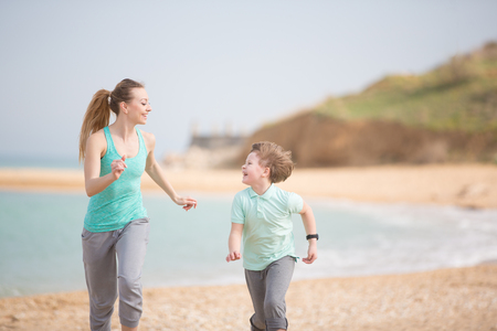 Mother with son running on the beach at morningの写真素材
