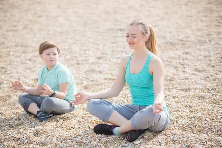 Mother with son exercising on the beach at morningの写真素材