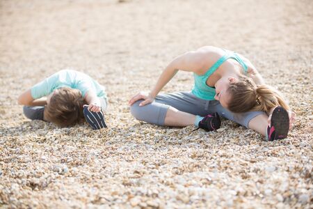 Mother with son exercising on the beach at morningの写真素材