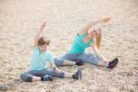 Mother with son exercising on the beach at morningの写真素材