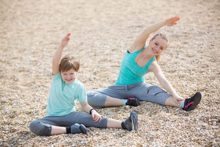 Mother with son exercising on the beach at morningの写真素材