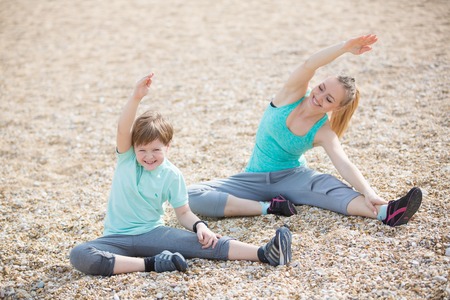 Mother with son exercising on the beach at morningの写真素材