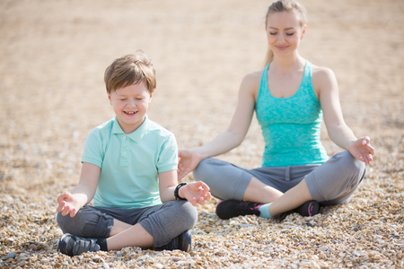 Mother with son exercising on the beach at morningの写真素材