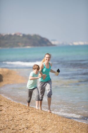 Mother with son running on the beach at morningの写真素材