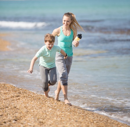 Mother with son running on the beach at morningの写真素材