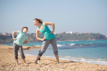 Mother with son exercising on the beach at morningの写真素材