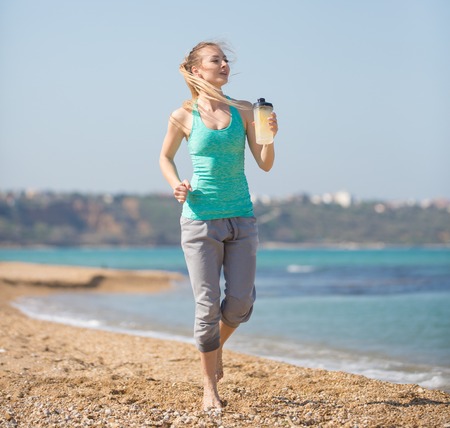 Young beautiful woman running on the beach at morningの写真素材