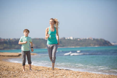 Mother with son running on the beach at morningの写真素材