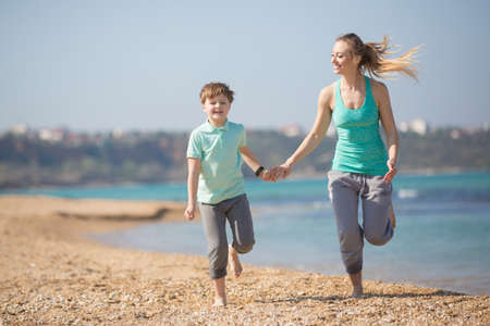 Mother with son running on the beach at morningの写真素材