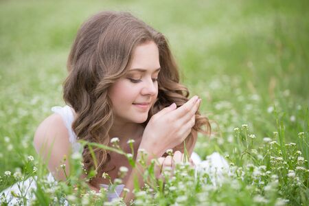 Young beautiful woman lying on the grass and smilingの写真素材