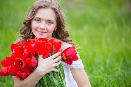 Young woman with red tulip flowers bouquetの写真素材