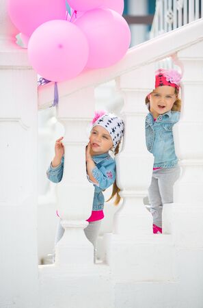 Happy little girls playing on the street with pink balloons.の写真素材