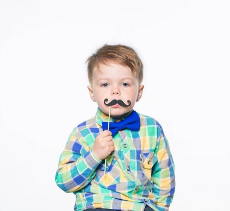 Cheerful little boy posing in studio with paper mustache. Isolated on white background.の写真素材