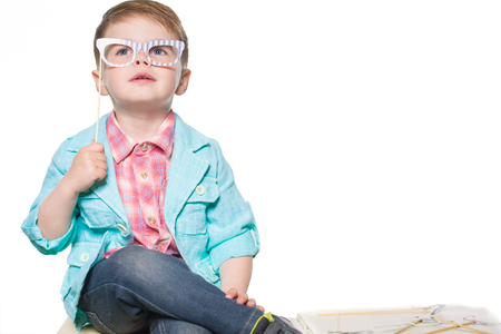 Cheerful little boy posing in studio with paper glasses. Isolated on white background.の写真素材