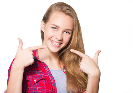 Close up portrait of smiling teen girl showing dental braces. Isolated on white background.の写真素材