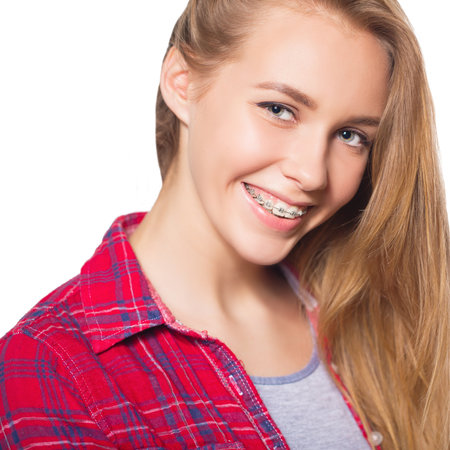 Close up portrait of smiling teen girl showing dental braces. Isolated on white background.の写真素材