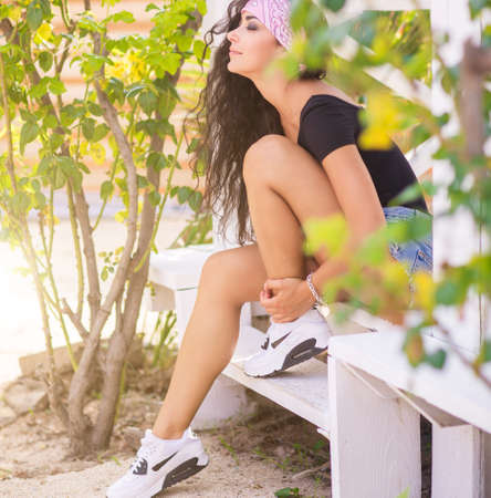Beautiful young woman with long dark hair posing in garden.の写真素材