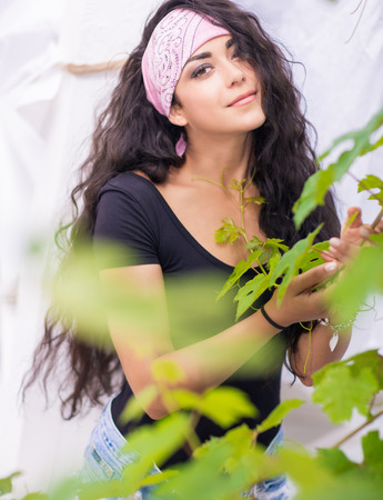 Beautiful young woman with long dark hair posing in garden.の写真素材