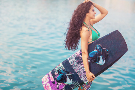 Young attractive brunette woman posing with wakeboard on the beach.の写真素材