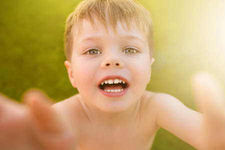 Little boy making selfie on the grass and smiling