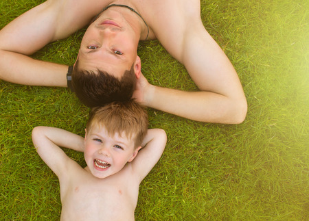 Father and son laying on the grass and smilingの写真素材