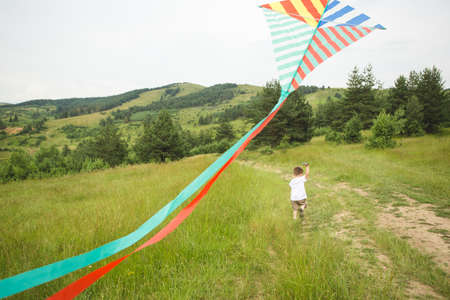 Little boy running with kite in countrysideの写真素材