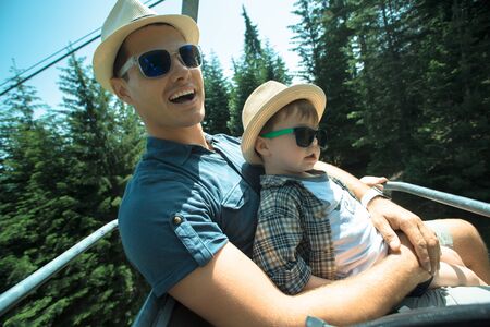 Father and little son using lift chair on the summer resort in Bulgariaの写真素材