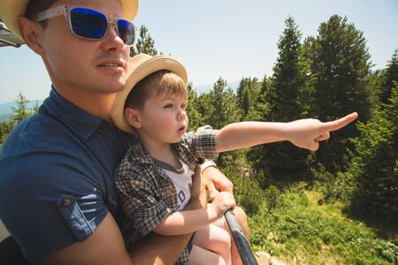 Father and little son using lift chair on the summer resort in Bulgariaの写真素材