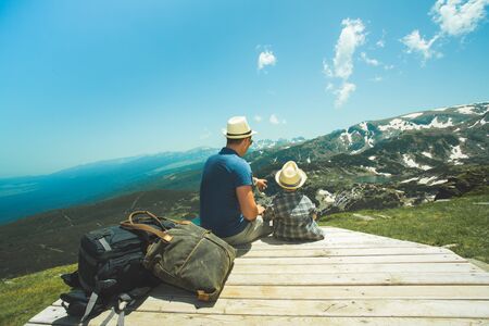 Father and his little son near the Seven lakes in Rila mountain, Bulgaria, Sitting and looking to the mountains.の写真素材