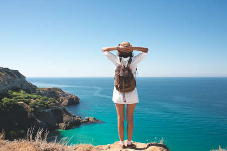 Backpack traveler woman standing on sea cliff .