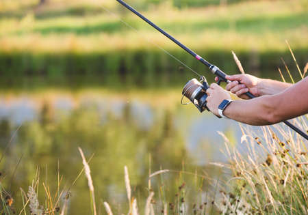 Man holding a fishing-rod on the foreground, and beautiful nature landscape on the backgroundの写真素材