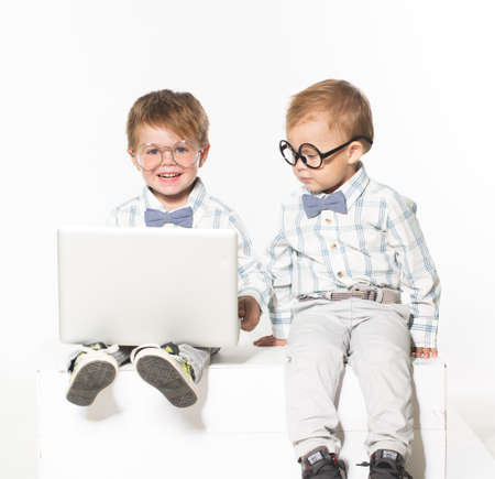 Two cute baby in business clothes with the glasses on the eyes with a laptop. Isolate photo in...