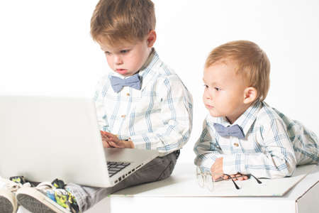 Two cute baby in business clothes with the glasses on the eyes with a laptop. Isolate photo in...