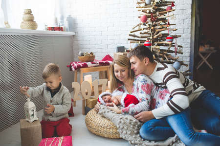 Portrait of cute couple and their babies near fashion xmas tree.の写真素材