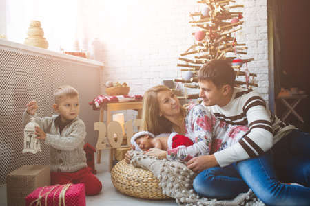 Portrait of cute couple and their babies near fashion xmas tree.の写真素材
