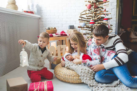 Portrait of cute couple and their babies near fashion xmas tree.の写真素材