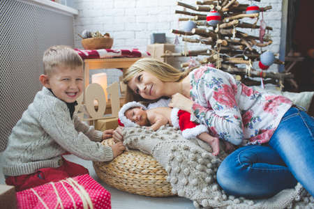 Portrait of young mom and her babies near fashion xmas tree.