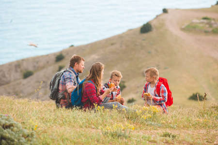 happy family of four people eating fastfood in mountains. family conceptの写真素材