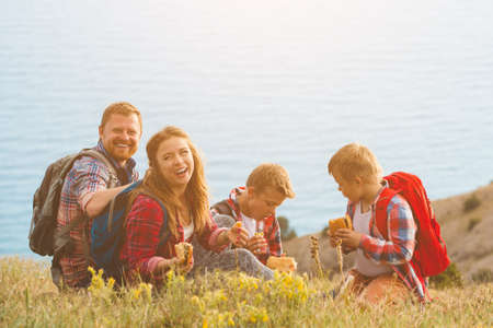 happy family of four people eating fastfood in mountains. family conceptの写真素材