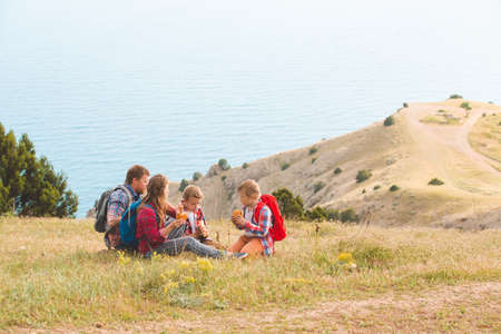 happy family of four people eating fastfood in mountains. family concept