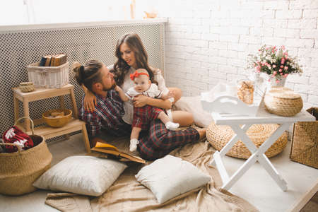 Parents with little baby reading story indoorsの写真素材