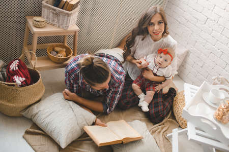 Parents with little baby reading story indoorsの写真素材