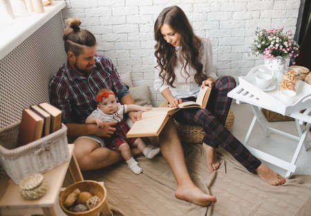 Parents with little baby reading story indoors