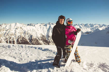 Happy couple of snowboarders in colorful and black jackets having fun.