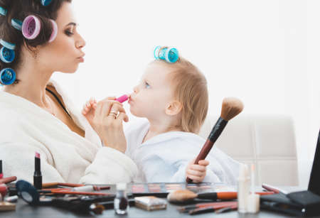 Beautiful woman and her daughter doing make upの写真素材