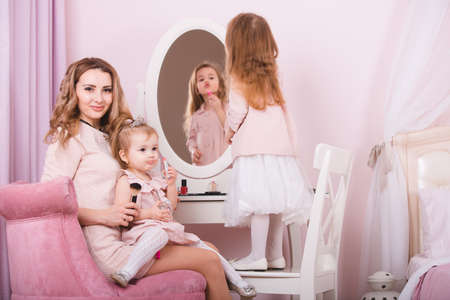 Mother and two daughters doing lip make-up.の写真素材