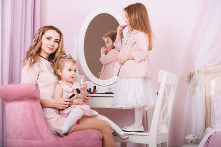 Mother and two daughters doing lip make-up.の写真素材